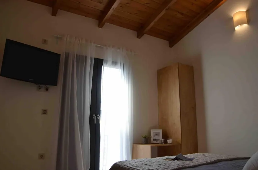Υπνοδωμάτιο με ξύλινη οροφή, τηλεόραση και πόρτα προς το μπαλκόνι